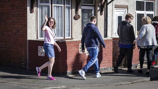 Student waving walking in the community